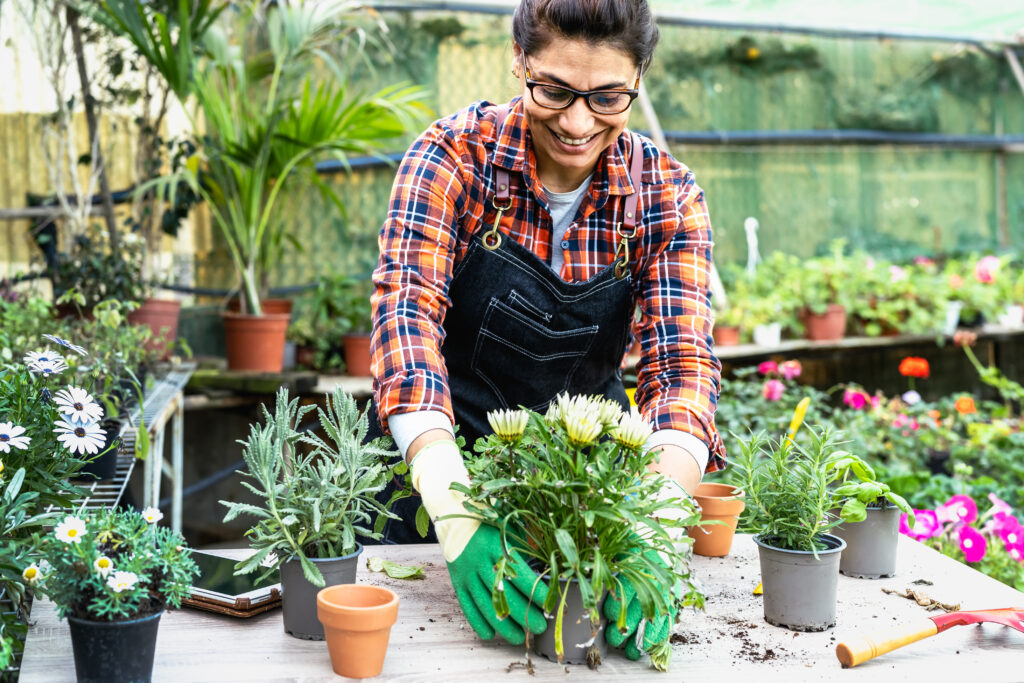 smiling hispanic woman working in a greenhouse with flowers